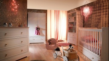 Zestaw białych mebli z szafą na ubrania i łóżeczkiem z szufladą w pokoju dziecięcym z drewnianą podłogą