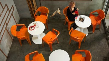 Designerskie pomarańczowe krzesła z podłokietnikami i stoły na jednej nodze z okrągłym blatem