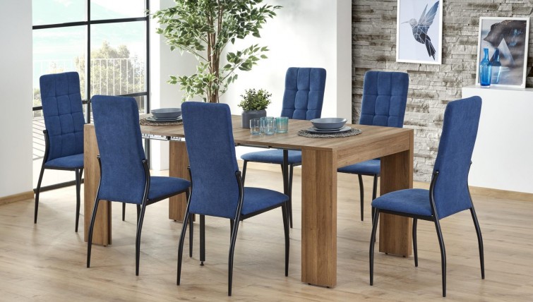 Stół w kolorze drewna z rozkładanym blatem i niebieskie krzesła pikowane na metalowych nogach