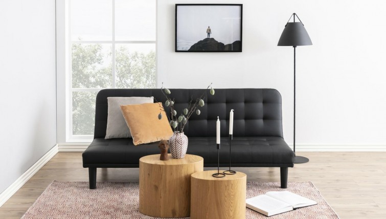 Rustykalny salon z czarną pikowaną kanapą i stolikami z tworzywa sztucznego