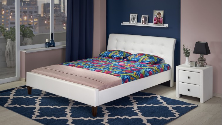 Białe łóżko z tapicerowaną szafką nocną w stylowej sypialni