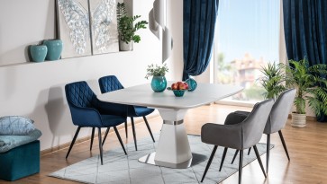 Biały stół kwadratowy z niebieskimi i szarymi krzesłami w przestronnej jadalni z dużym oknem