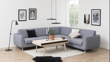 Skandynawski salon z dużą kanapą narożną w kolorze szarym i bielonym stolikiem