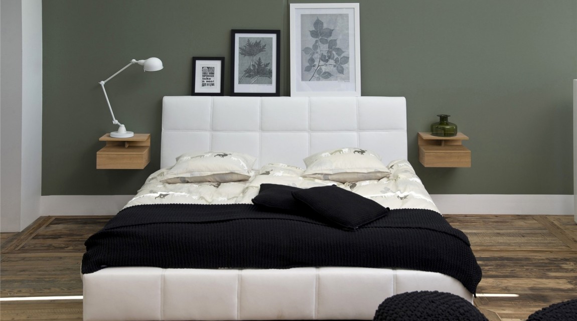Nowoczesna sypialnia z białym łóżkiem z pikowanej ekoskóry i ciemnozielonymi ścianami