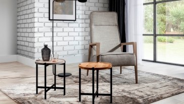 Strefa wypoczynkowa z tapicerowanym fotelem i okrągłymi stolikami w stylu loft