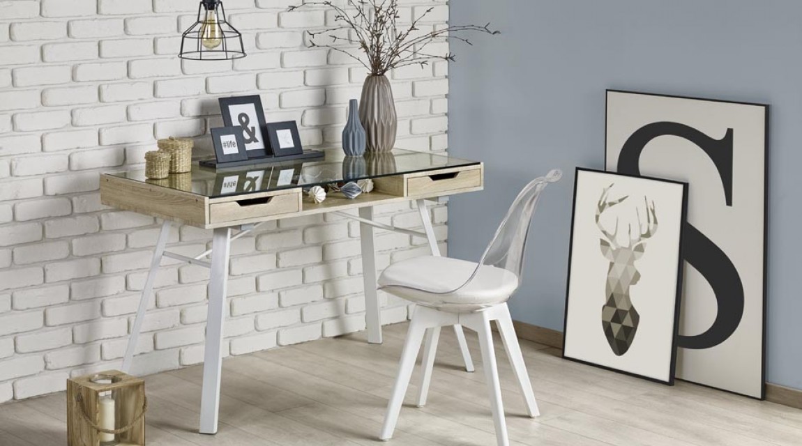 Biurko ze szklanym blatem w towarzystwie krzesła z tapicerowaną poduszką w otoczeniu szarej i ceglanej ściany