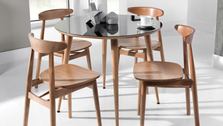 Okrągły stół ze szklanym blatem w towarzystwie drewnianych krzeseł na nogach