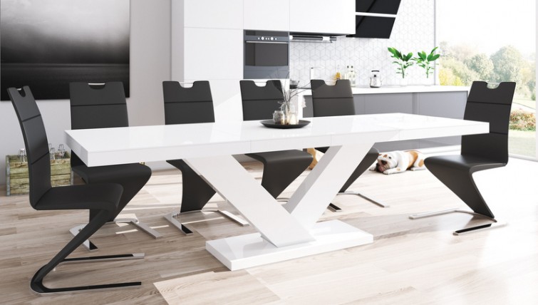 Biały stół rozkładany do 2,5 metrów o połyskującej powierzchni i czarne krzesła z ekoskóry w jadalni połączonej z salonem i kuchnią