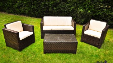 Technorattanowy zestaw mebli z sofą, fotelami i stolikiem w zielonym ogrodzie