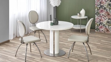 Okrągły stół w wysokim połysku w towarzystwie tapicerowanych krzeseł w nowoczesnej jadalni