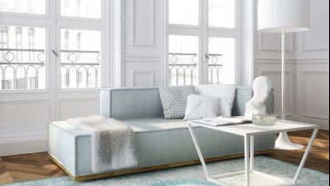 Stolik z marmurowym blatem i tapicerowana sofa w salonie z dużymi oknami i balkonem
