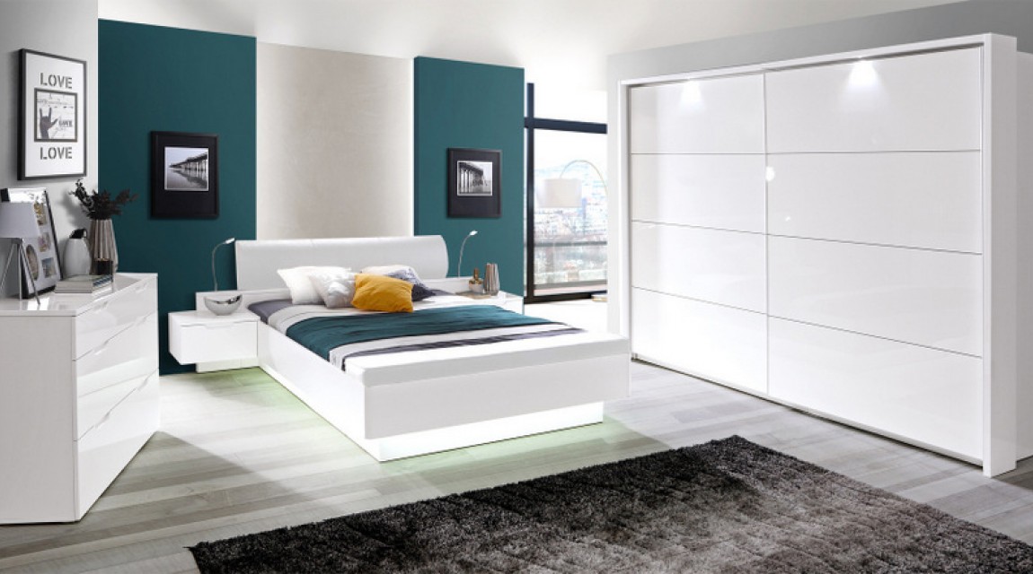 Białe łóżko z szafkami nocnymi i komoda z frontami o połyskującej powierzchni