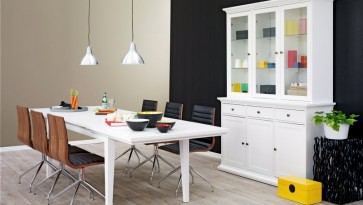 Rozkładany biały stół dla sześcioosobowej rodziny oraz kredens z szufladami i przeszklonymi drzwiami