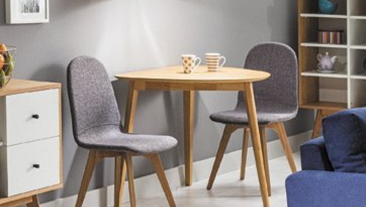 Drewniany stół z półokrągłym blatem na trzech nogach i szare tapicerowane krzesła na drewnianej podstawie