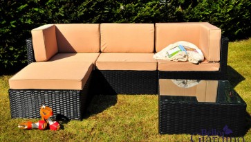Narożna sofa z poduszkami i stolik ze szklaną nakładką w ogrodzie