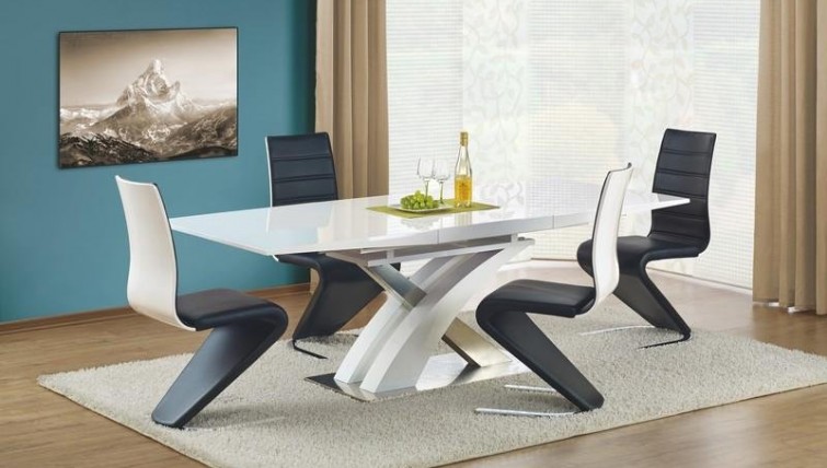Lakierowany stół z elementami ze stali nierdzewnej w towarzystwie czarnych krzeseł z ekoskóry