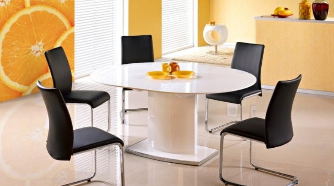Biały stół lakierowany z owalnym blatem rozkładanym i czarne krzesła na metalowych płozach