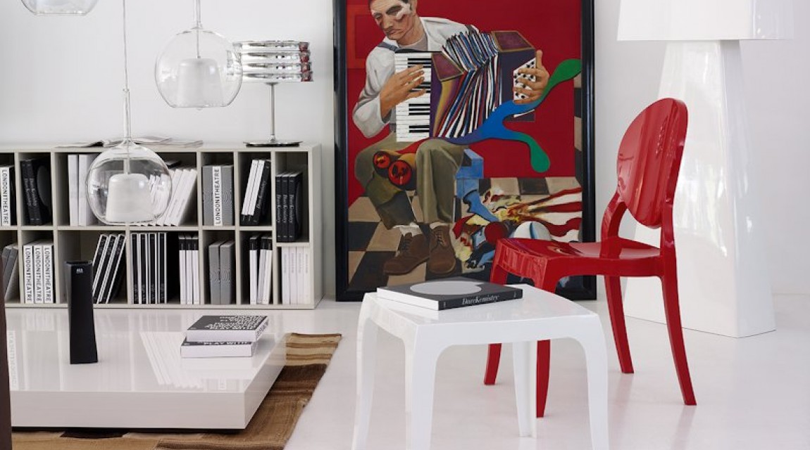 Czerwone krzesło o połyskującej powierzchni bez podłokietników i biały stolik pomocniczy w awangardowym wnętrzu salonowym