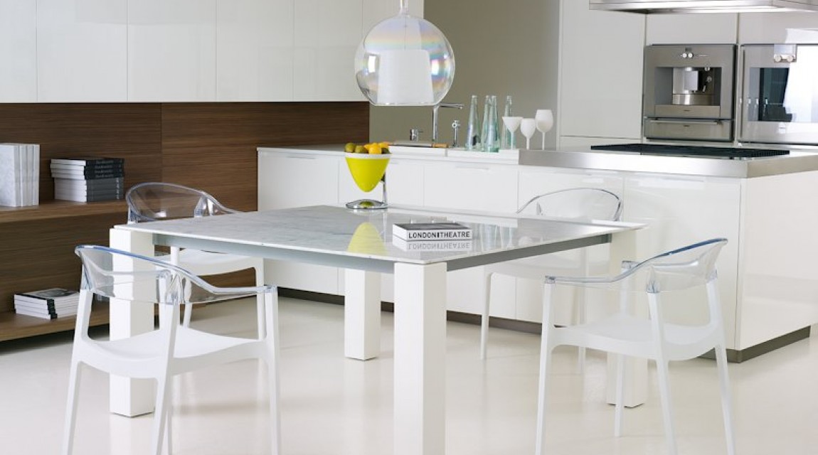 Białe krzesła kuchenne z przezroczystym oparciem i nierozkładany stół jako uzupełnienie przestronnej jadalni