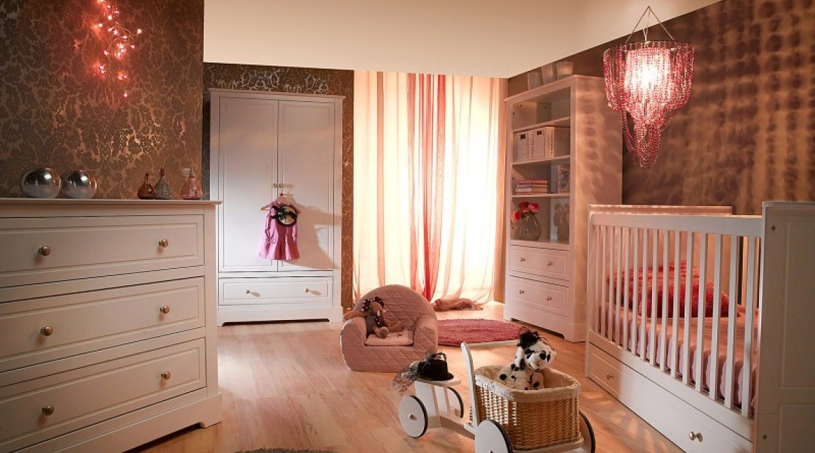Zestaw białych mebli z szafą na ubrania i łóżeczkiem z szufladą w pokoju dziecięcym z drewnianą podłogą