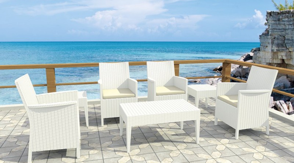 Wypoczynkowe fotele ogrodowe z wysokimi podłokietnikami oraz stoliki kawowe i prostokątna ława