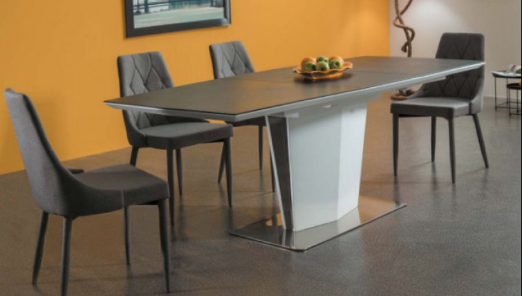 Rozkładany stół ze szklanym prostokątnym blatem i szare pikowane krzesła bez podłokietników