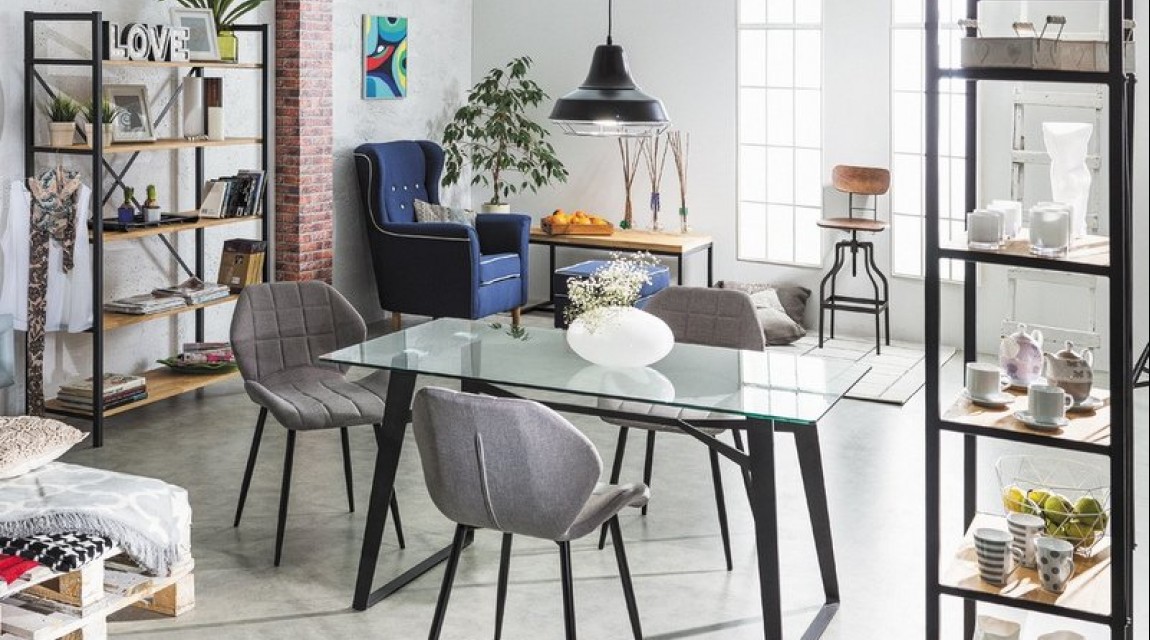 Pojemne regały półkowe w stylu industrialnym oraz stół ze szklanym blatem i tapicerowane krzesła