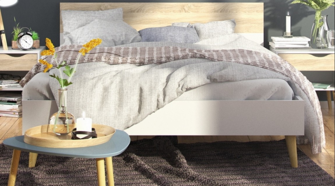 Łóżko na drewnianych nóżkach w stylu skandynawskim w nowoczesnej sypialni na tle szarych ścian