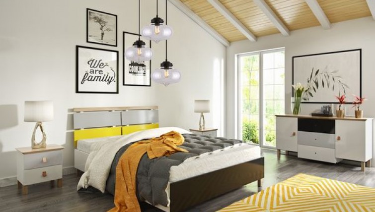 Komoda i szafki nocne z kolorowymi frontami oraz łóżko na wysokich nóżkach i szklana lampa wisząca
