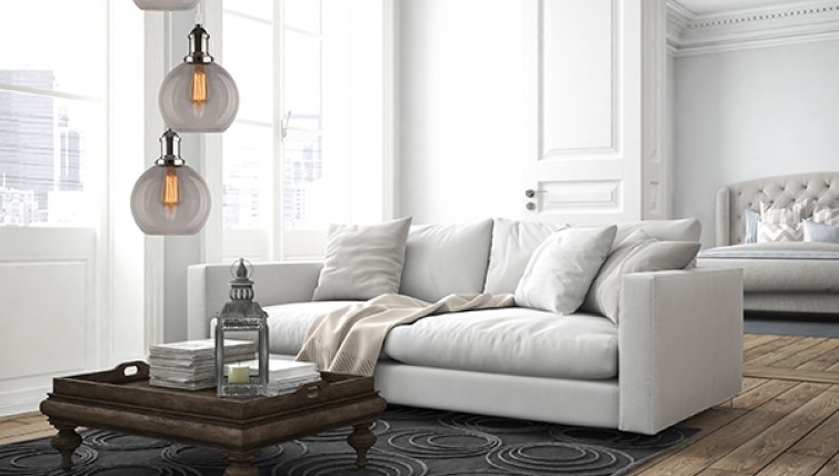 Lampa wisząca z trzema szklanymi kloszami oraz stylowa sofa z miękkimi poduszkami
