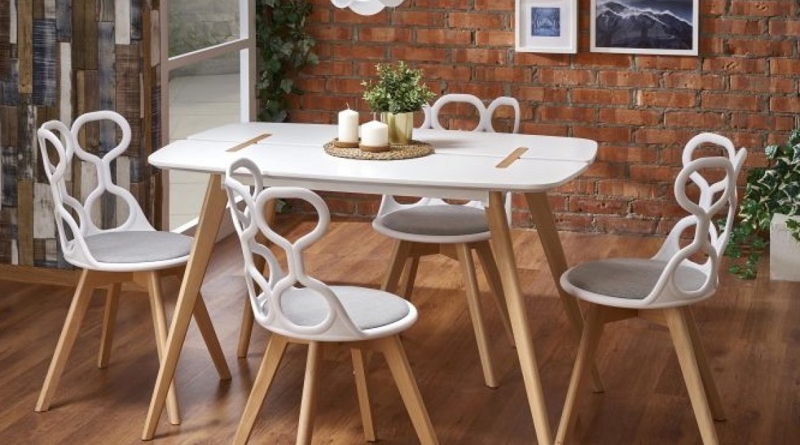 Biały stół z elementami w kolorze drewna oraz krzesła ze zdobionym oparciem