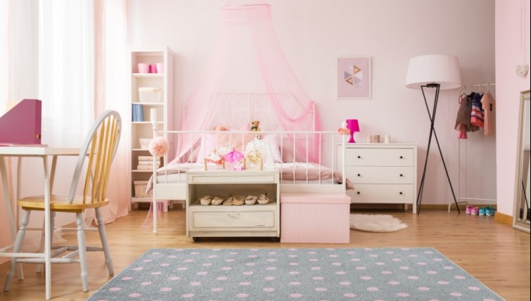 Szary dywan w różowe groszki oraz łóżko uzupełnione bajkowym baldachimem