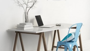 Drewniane biurko i niebieskie krzesło z metalu oraz wisząca lampa w stylu industrialnym