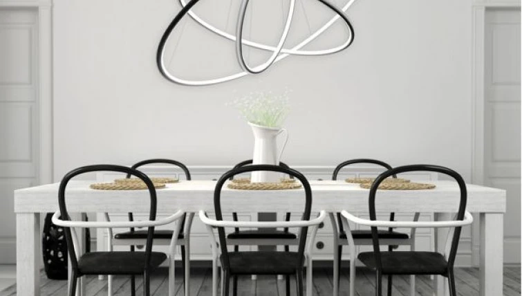 Designerskie krzesła z podłokietnikami oraz biały stół i futurystyczna lampa sufitowa