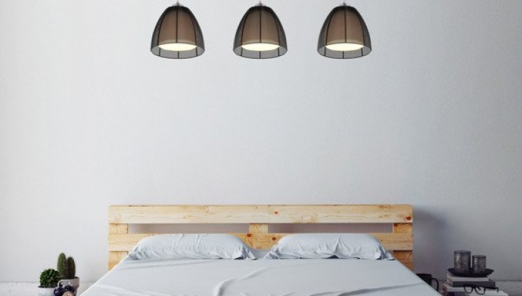 Potrójna lampa z metalowymi kloszami i dwuosobowe łóżko w naturalnym odcieniu drewna