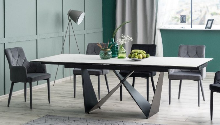 Designerski stół na metalowej podstawie z pikowanymi krzesłami w jadalni z zielonymi ścianami