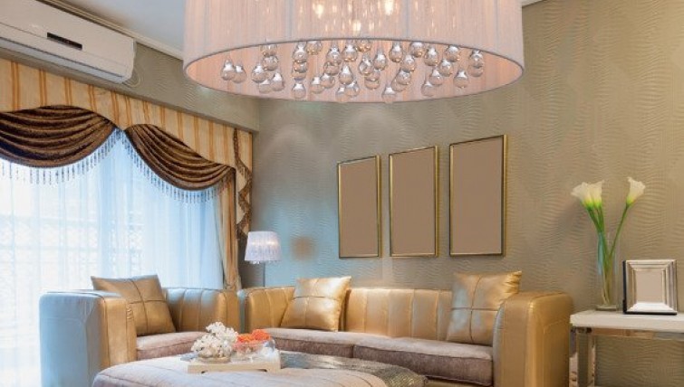 Designerska lampa wisząca i tapicerowana sofa w eleganckim złotym kolorze