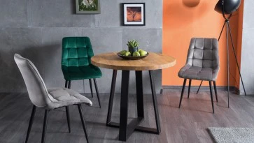 Okrągły stół w stylu industrialnym z tapicerowanymi krzesłami w jadalni połączonej z salonem