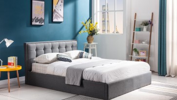 Wysokie łóżko dla dwóch osób z szarej tkaniny z pikowanym zagłówkiem i pojemnikiem na pościel