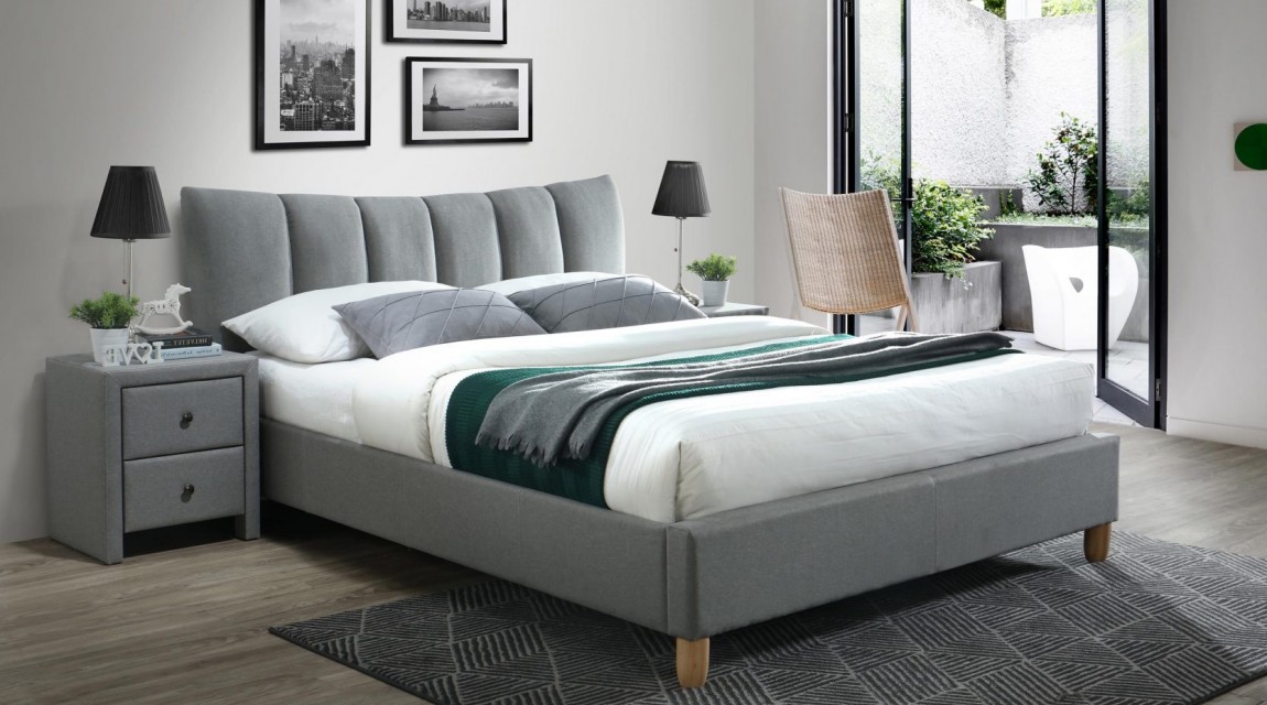 Tapicerowane łóżko na drewnianych nogach z wysokim zagłówkiem i szafka nocna z szufladami