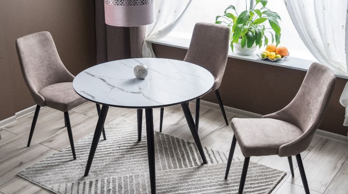 Okrągły stół na metalowych nogach z tapicerowanymi krzesłami na popielatym dywanie