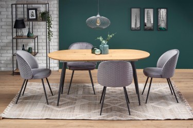 Owalny stół z tapicerowanymi krzesłami na czterech nogach w loftowej jadalni