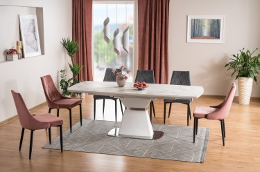 Duży stół ceramiczny w kolorze białym i tapicerowane krzesła z pikowanym siedziskiem w otwartej jadalni połączonej z salonem