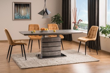 Stół z funkcją rozkładania imitujący strukturę betonu i pikowane krzesła aksamitne w salonie połączonym z jadalnią