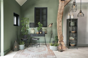 Metalowe meble i lampy w bocznej części salonu z zielonymi ścianami
