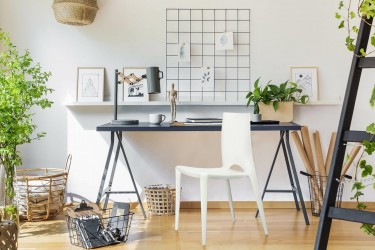 Biuro w stylu loftowym z metalowym biurkiem i designerskim krzesłem z tworzywa