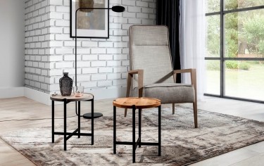 Strefa wypoczynkowa z tapicerowanym fotelem i okrągłymi stolikami w stylu loft
