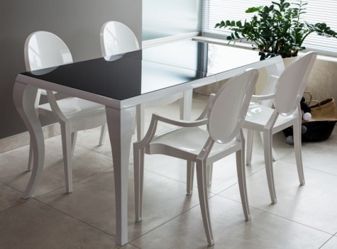 Elegancki stół ze szklanym blatem w towarzystwie designerskich białych krzeseł z podłokietnikami w minimalistycznej jadalni