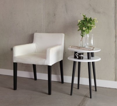 Stolik kawowy i tapicerowany fotel w jednakowej kolorystyce na tle betonowej ściany