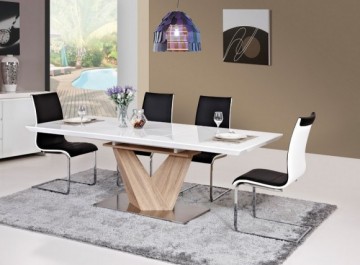 Biało-czarne krzesła na metalowych płozach i biały rozkładany stół z blatem o połyskującej powierzchni